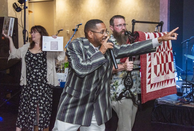 The live auction for this quilt is lively. Shown are Bonnie Golden, auctioneer Ephrem Phillips and Dan Pope.